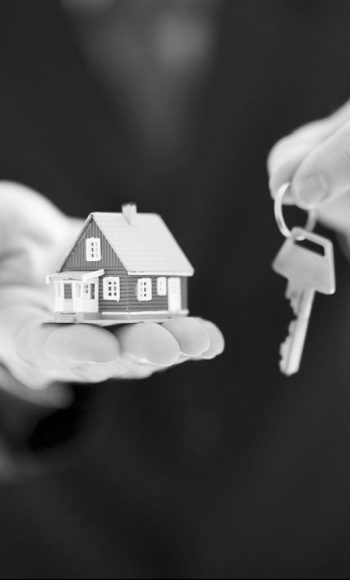 Cropped image of a male holding model house with key in hand isolated on white background